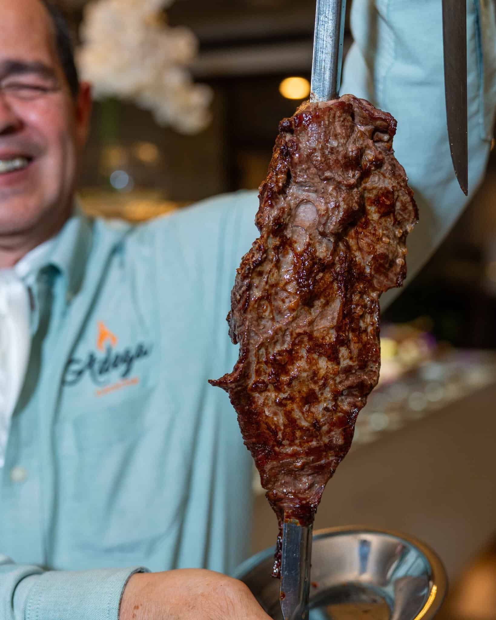 This image shows the Brazilian Churrasco During Orlando Magical Dining in the hands of Gaucho chef.