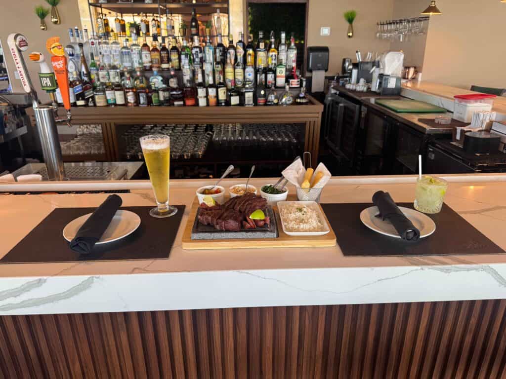 A Brazilian-style Picanha steak on a stone board, served at a bar with beer and cocktails at this steakhouse near Disney World