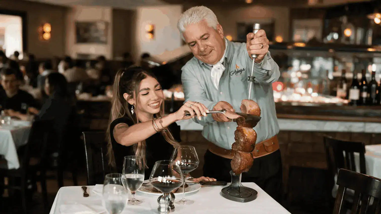 Gaucho carving churrasco tableside during rodizio service at Adega Gaucha Brazilian steakhouse